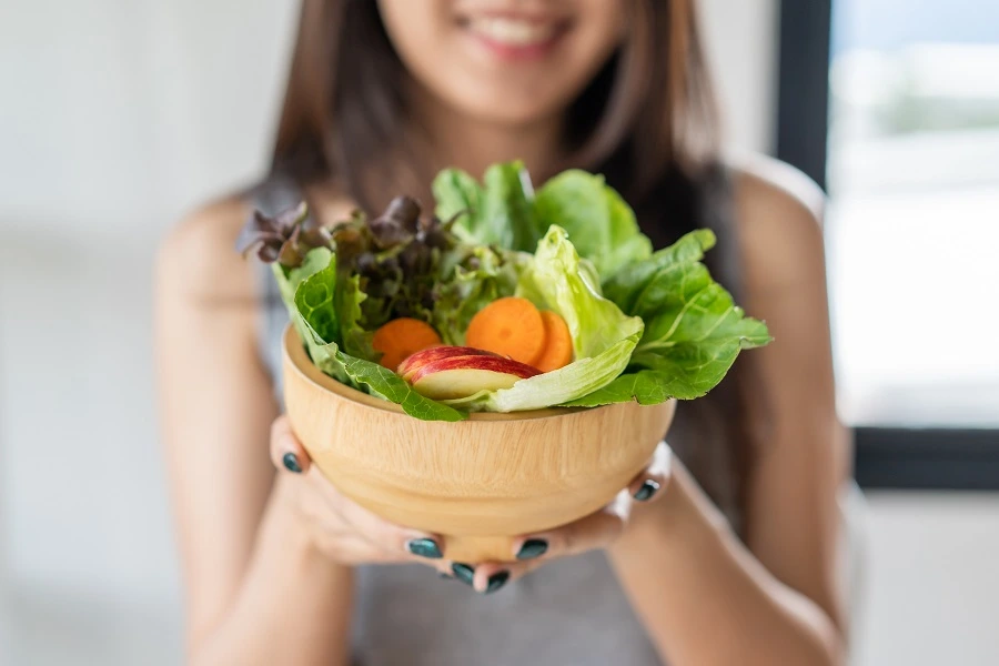 young woman with bowl of fresh salad